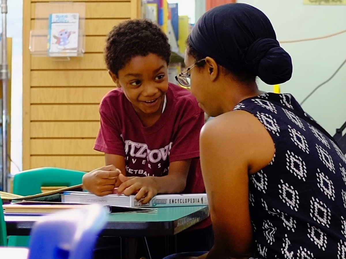 boy and woman talking at table at library
